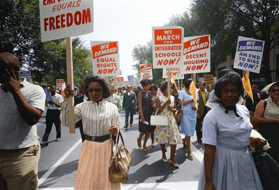 在华盛顿举行的游行中，示威者手持要求投票权和平等民权的标语沿着街道行走